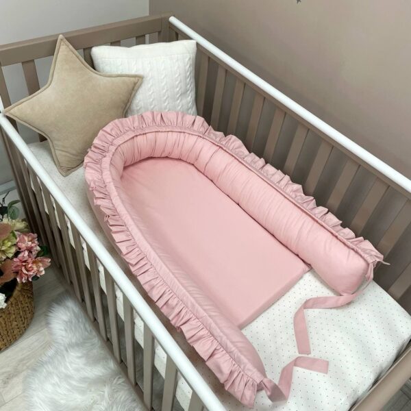 Baby nest roz cu volănașe desfăcut, cu laterala întinsă lângă saltea
