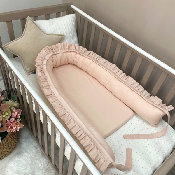 Baby nest cu volănașe crem cu funda desfăcută, laterala întinsă și salteaua la vedere