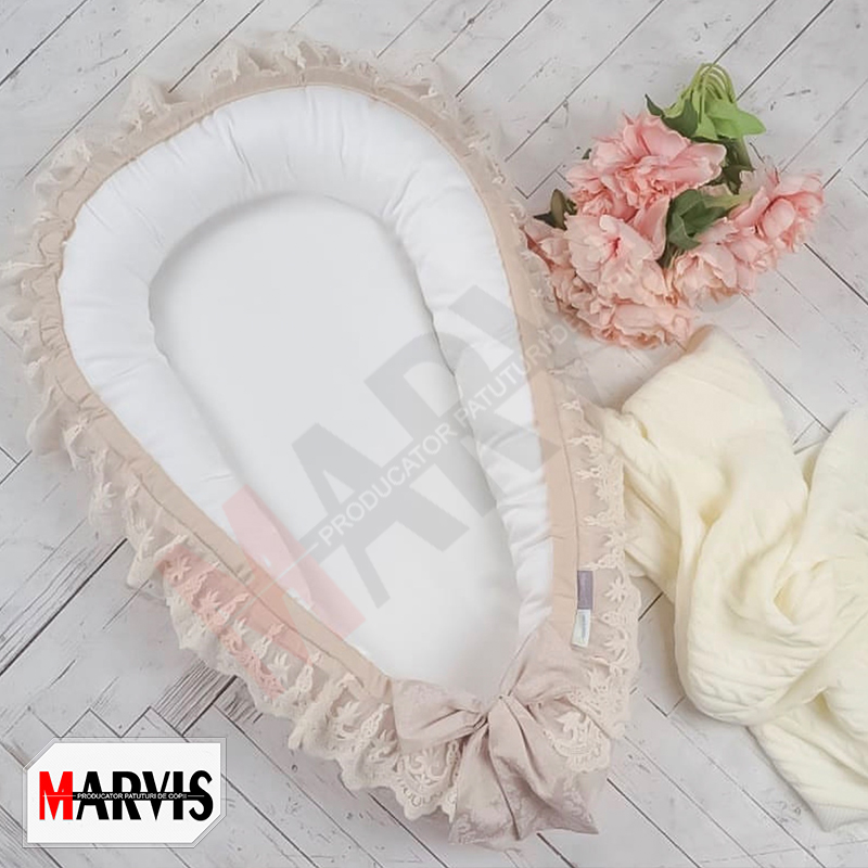 Baby Nest Fancy crem, vedere de sus Baby Nest Fancy crem cu interior alb, laterale crem, volan de dantelă ivoire și fundă, pe o podea albă