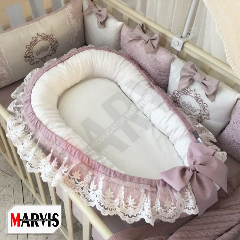 Baby Nest Fancy roz, vedere de ansamblu Baby Nest Fancy roz cu interior alb, laterale roz prăfuit, volan de dantelă albă și fundă, într-un pătuț