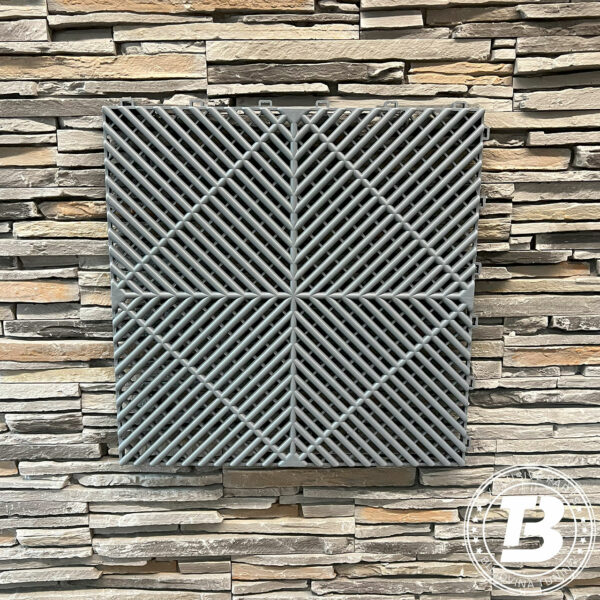 Placă de pardoseală modulară ventilată gri, cu grilaj în model de romb, pe un perete din piatră