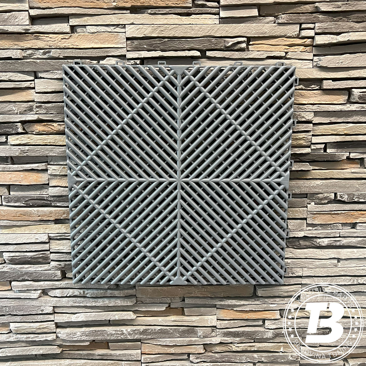 Placă modulară ventilată gri, pe perete din piatră Placă de pardoseală modulară ventilată gri, cu grilaj în model de romb, pe un perete din piatră