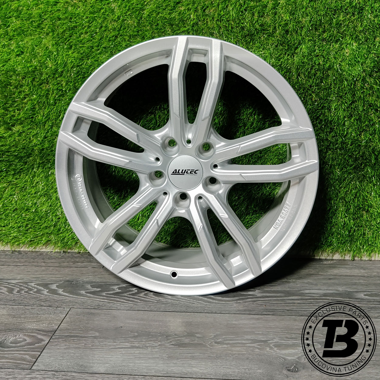 Jantă Alutec Drive Polar Silber R18, vedere din față Jantă Alutec Drive Polar Silber R18 5×112, argintie, cu cinci spițe duble, sprijinită de un perete verde