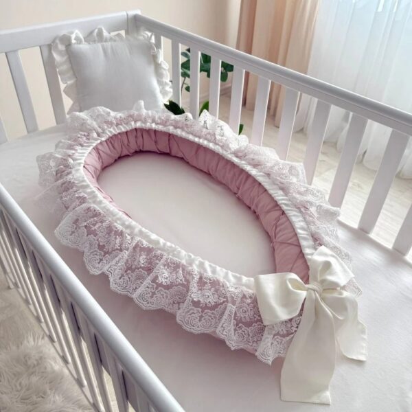 Baby Nest Classic roz cu dantelă albă și fundă ivoire, într-un pătuț alb, vedere de ansamblu