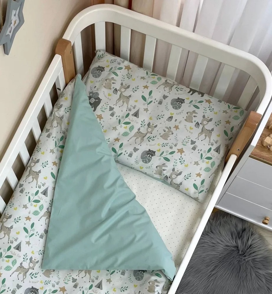Set lenjerie de schimb Bambi cu prietenii Lenjerie Bambi cu prietenii în pătuț, cu husa împăturită și fața verde mentă vizibilă