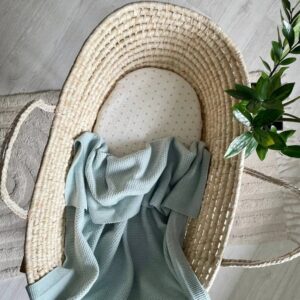 Păturica Cosy verde mentă într-un coș împletit din fibre naturale, văzută de sus