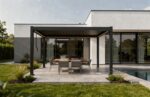 Pergola X 2.0 în varianta gri antracit, pe terasa unei case moderne, cu masă de exterior lângă piscină
