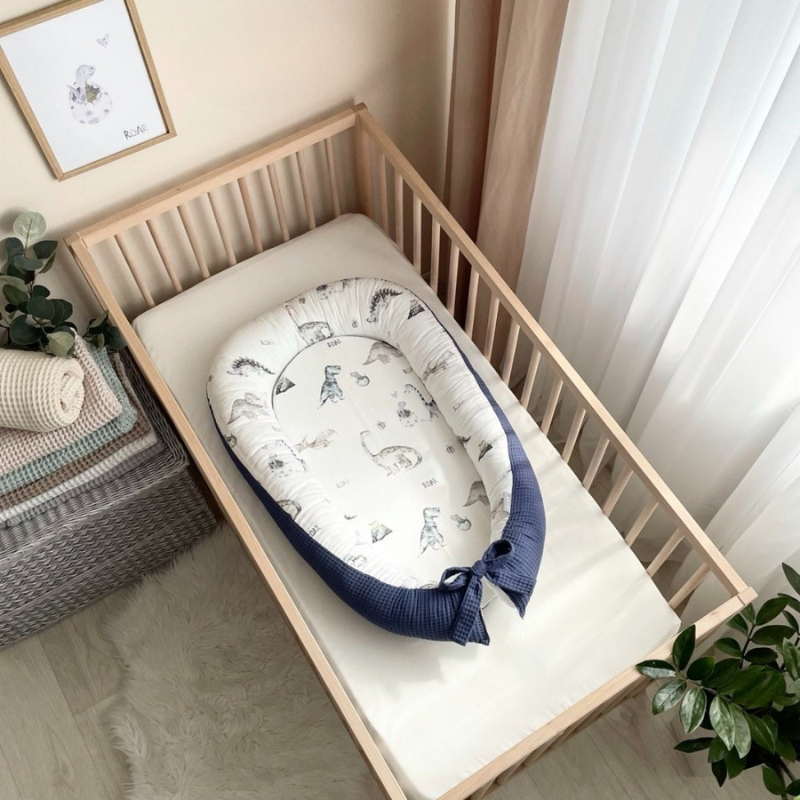 Baby nest Dino albastru Baby nest Dino albastru cu dinozauri pe fond alb și exterior din vafe albastru închis, așezat în pătuț
