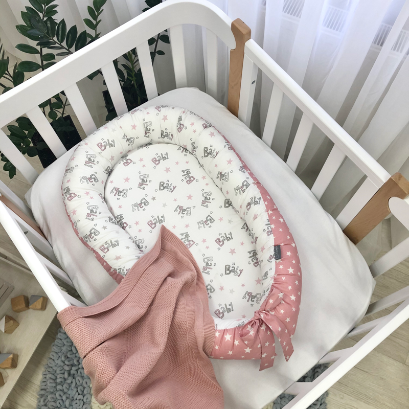 Baby stars roz, fața albă Baby nest Baby stars roz pe fața albă cu inscripții Baby, cu fundă roz cu steluțe, în pătuț