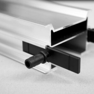 Adaptor Relo A din plastic negru introdus în canalul unui profil de aluminiu argintiu, cu știftul cilindric în față