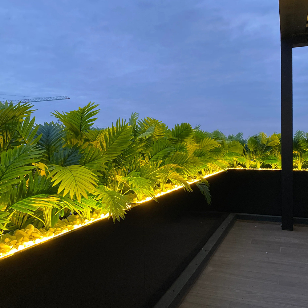 Jardiniere cu ferigă artificială iluminate LED Jardiniere negre cu ferigă artificială și bandă LED pe conturul unei terase, la apus