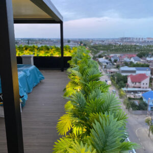 Terasă cu pergolă și jardiniere cu frunze artificiale iluminate, cu vedere spre oraș