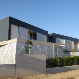 Casă cu etajul încins de benzi din plăci Fundermax 0070 Carbon Grey, gri-antracit, deasupra unui soclu din piatră gri