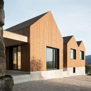 Casă cu acoperiș în două ape, placată vertical cu profile Luna UTV din pin tratat termic, cu soclu alb de beton