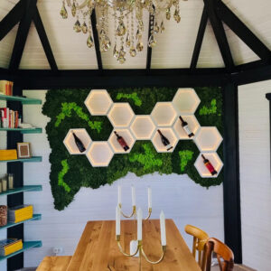 Fundal de mușchi stabilizat verde cu rafturi hexagonale albe luminate LED și sticle de vin, deasupra unei mese din lemn