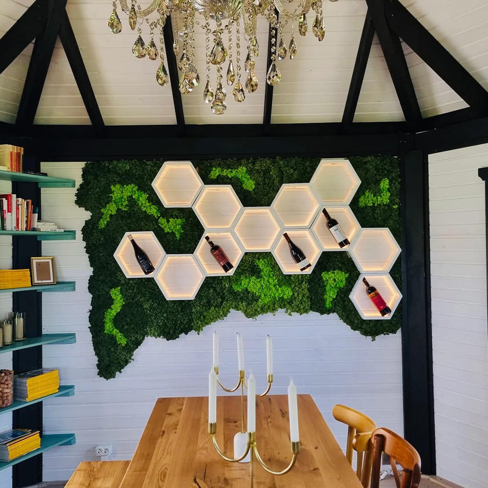 Compoziție cu rafturi hexagonale și fundal din mușchi stabilizat Fundal de mușchi stabilizat verde cu rafturi hexagonale albe luminate LED și sticle de vin, deasupra unei mese din lemn