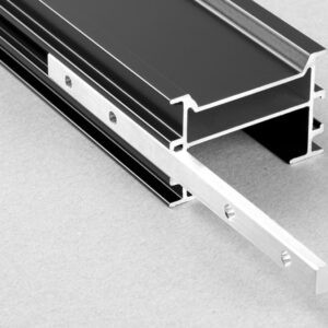 Element de îmbinare Relo L introdus pe jumătate în canalul unui profil negru de aluminiu, gata pentru profilul următor