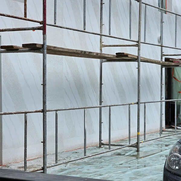 Fațadă cu efect de travertin în dungi diagonale, aflată încă sub schelă