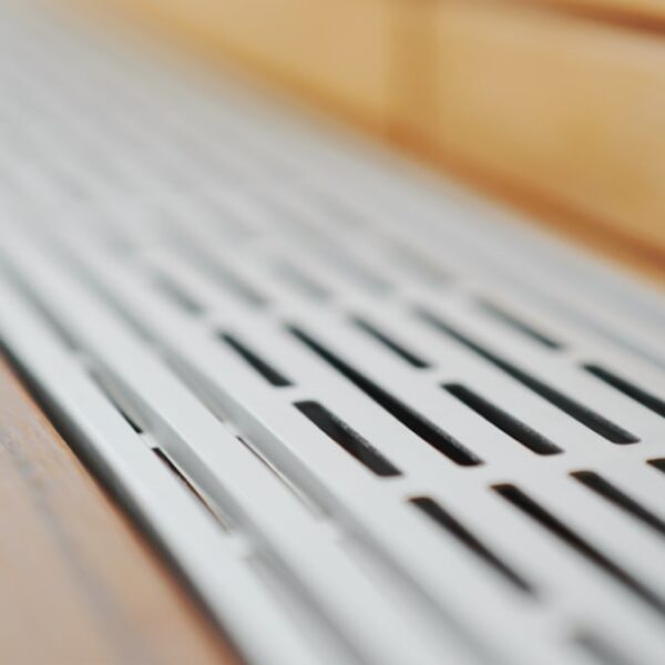 Grila de ventilație Relo V din aluminiu anodizat, văzută de aproape, cu fantele alungite care lasă aerul să circule sub terasă