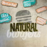 Inscripția „Natural” din mușchi stabilizat într-un restaurant, printre plăcuțe din lemn pictate
