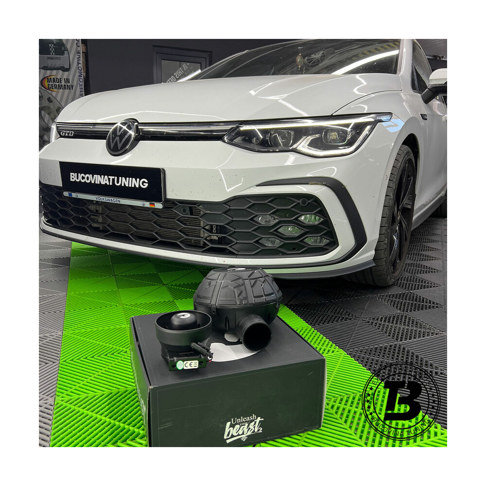 Maxhaust cu două generatoare, cu montaj inclus Generator de sunet Maxhaust pe cutia setului, în fața unui VW Golf alb dintr-un atelier