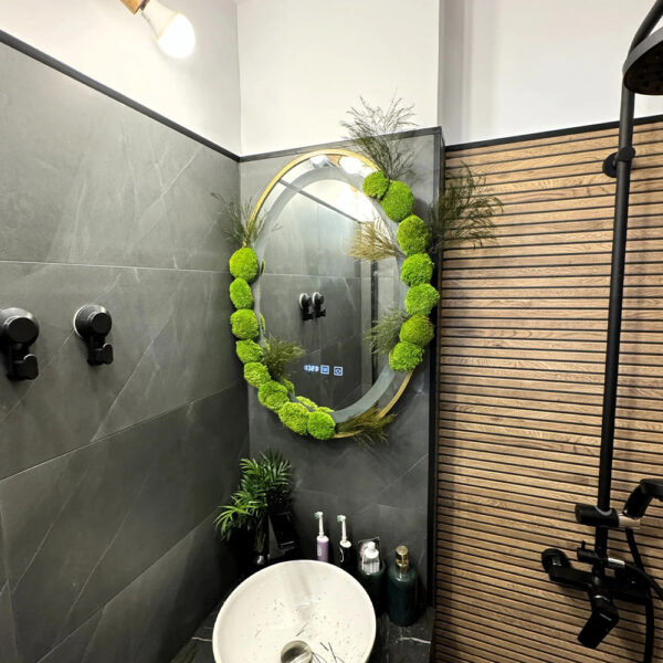 Oglindă rotundă cu mușchi stabilizat deasupra unui lavoar alb, într-o baie cu lamele din lemn