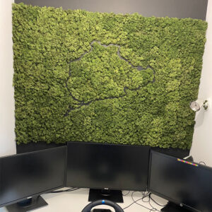 Panou din licheni stabilizați verzi cu traseul unui circuit de curse gravat, deasupra unui birou cu trei monitoare
