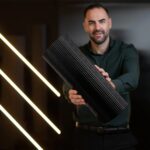 Bărbat care ține în mâini un panou canelat negru lucios rulat în cilindru