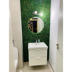 Baie îngustă cu perete din licheni verzi, oglindă rotundă și mobilier alb de lavoar