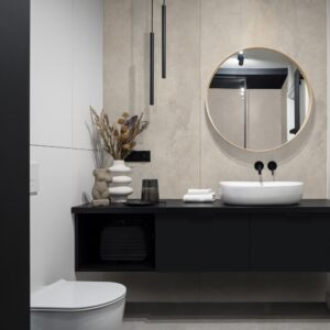 Baie cu oglindă rotundă cu ramă de lemn, lavoar alb pe blat negru și lămpi negre tubulare, pe un perete Rocko R267 Urban Grid