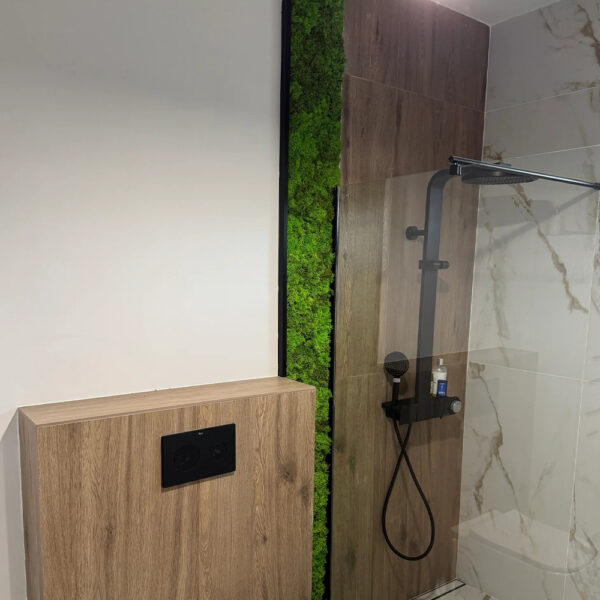 Baie modernă cu placaj din lemn, marmură albă și o fâșie verticală de licheni verzi lângă duș