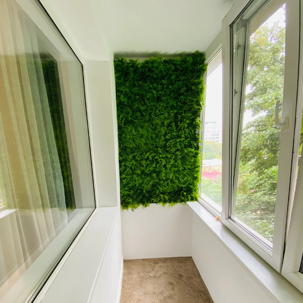Perete verde artificial pe balcon închis Perete verde artificial din plante sintetice pe peretele lateral al unui balcon închis