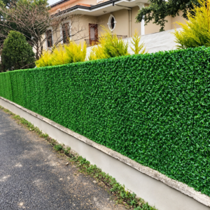 Gard viu artificial verde pe zidul unei curți, lângă o alee